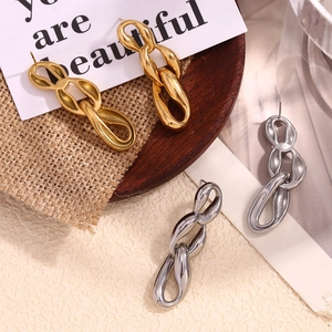 Three-link chain earrings in gold and silver finish on a rustic wooden tray