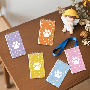 Five colorful spiral notebooks with white paw prints and bone patterns on wood table
