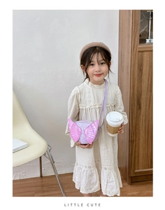 Girl wearing a purple crossbody bag with sequined angel wings in a bright room