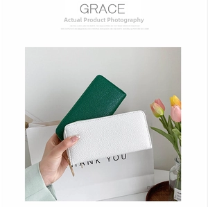 Detail of lychee pattern PU leather wallets in dark green and white with gold zippers