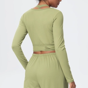 Close-up of olive green long-sleeve crop top with cross-strap back and matching leggings