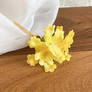 Detail of handmade yellow fabric flower hair pin with elegant gold U-shaped metal fork