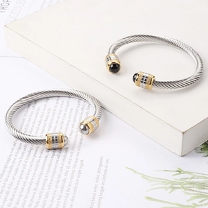 Detail of twisted cable steel bracelets with black onyx inlay on white stone