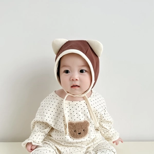 Close-up of newborn cotton baby suit featuring bear applique and dotted pattern texture