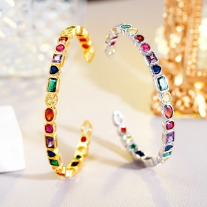 Detail of gold and silver open bangles featuring colorful square and round gemstones