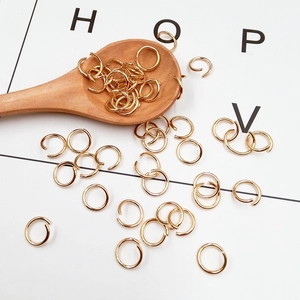 Golden metal open jump rings for DIY jewelry making displayed in a wooden spoon