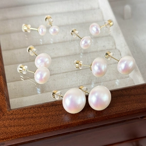 Detail view of five sizes of pink pearl stud earrings in a luxury jewelry box