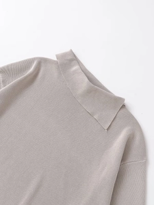 Detailed close-up of the light gray knit sweater showing the collar and shoulder stitching