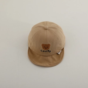 Close-up of khaki baby cap with brown bear embroidery and Lucky text on soft cotton fabric