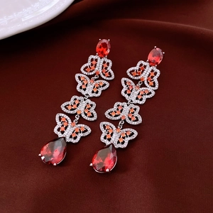 Detail view of silver drop earrings featuring red pear-cut stones and butterfly links
