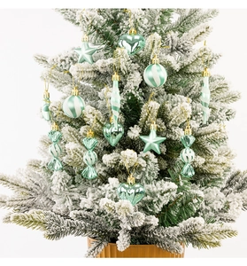 Detail view of mint green Christmas ornaments with glitter finish on a snowy tree