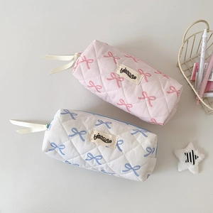 Close-up of quilted bow pattern pencil case with brand label and ribbon detail