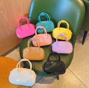 Collection of colorful mini PVC jelly handbags in eight candy tones on a green chair