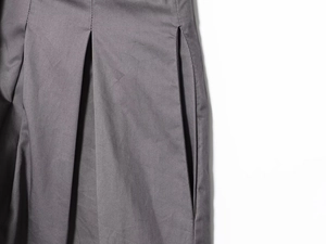 Close-up of grey twill fabric shorts showing detailed pleats and pockets stitching