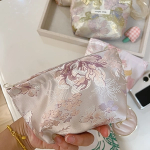 Close-up of pink floral jacquard fabric mini pouch with white zipper and metal handle