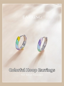 Macro shot of S925 sterling silver colorful enamel striped hoop earrings on wood