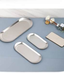 Three-piece stainless steel oval jewelry trays with brushed silver finish on a desktop
