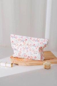 Close-up of floral jacquard cotton makeup bag with brand label on a wooden stand