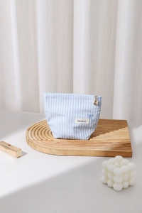 Détail d'une trousse de maquillage à rayures bleu clair avec broderie nœud et zip fleur