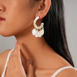 Gros plan de boucles d'oreilles dorées en C avec zircon et nacre portées par un mannequin