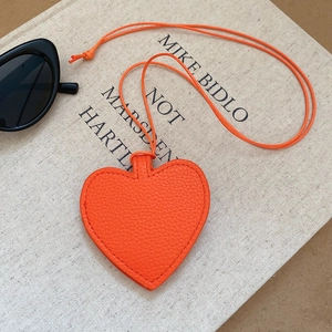 Close-up of orange heart-shaped leather pendant with lychee texture on art book