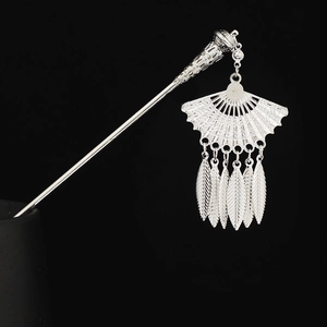 Detailed close-up of a silver ethnic hair stick with ornate fan pendant and leaf tassels