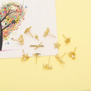 Detailed close-up of gold-plated stud earrings featuring star, flower, and lightning shapes