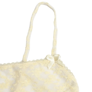 Detail of light yellow lace camisole showing delicate floral texture and satin bow