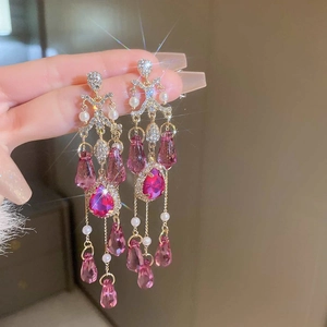 Detail of long fringe earrings with pink crystals and pearls in a hand-held close-up