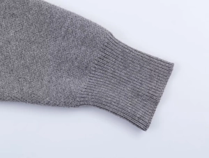 Close-up of gray knit sweater cuff showing fine ribbed texture and premium stitching detail