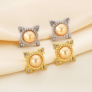 Macro shot of vintage baroque earrings with pearl center and rhinestones on satin fabric