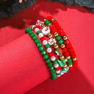 Detail of Christmas beaded bracelet set with snowman and tree charms on red background