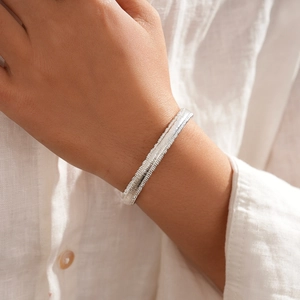 Detail of silver textured geometric bangle with snake bone pattern on a female wrist