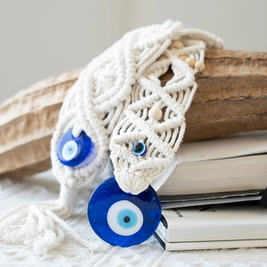 Detail of bohemian hand-woven macrame wall hanging with blue glass evil eye charms