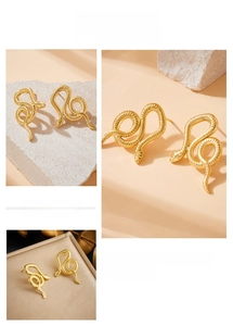 Macro detail of gold-plated snake stud earrings showing textured scales and coiled design