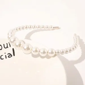 Detail view of white gradient pearl headband placed on a decorative ceramic plate