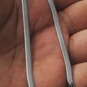 Close-up of a silver titanium steel flat snake chain necklace held in a hand