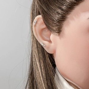 Star and angel wing cartilage piercing earrings with zircon insets on model
