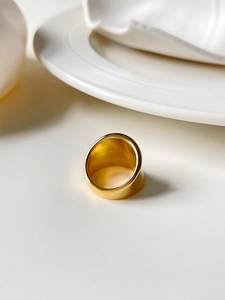 Detailed view of wide 18K gold plated titanium steel ring on a white surface