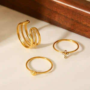 Detailed view of 3-piece gold stainless steel ring set with heart and cross accents