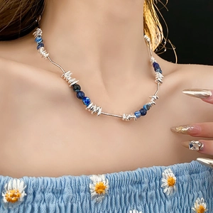 Close-up of geometric beaded necklace with blue marble beads and twisted silver metal elements