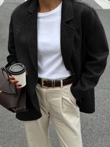 Detail of a dark grey blazer styled with a beige wide-leg pant and a burgundy belt