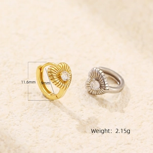 Macro shot of gold and silver heart earrings with striped texture and zircon details