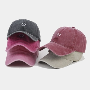 Detail of embroidered heart on vintage washed cotton baseball caps in multiple colors