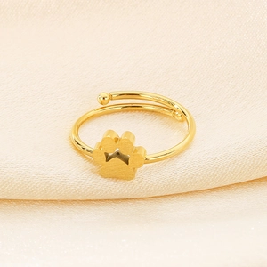 Detailed close-up of golden adjustable cat paw ring on beige silk background