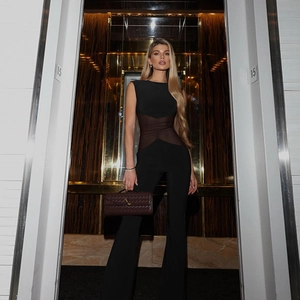 Detail of mesh patchwork on black slim-fit jumpsuit with sheer waist and flared legs