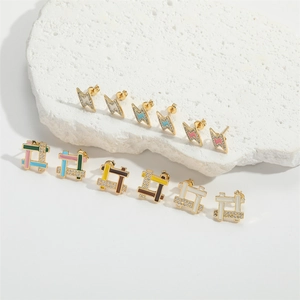 Close-up of enamel lightning bolt earrings with pavé zircons on a white stone base