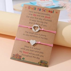 Dettaglio di due braccialetti rosa con cuori su un biglietto regalo per la scuola