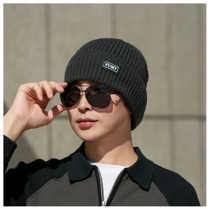 Close-up of the grey ribbed knit beanie with a FUMY fabric label and warm texture