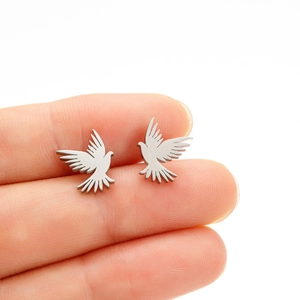 Macro detail of bird shaped stainless steel stud earrings held between fingertips